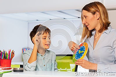 Woman teach boy with autism clock and hours Stock Photo