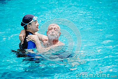 Woman teacher help to training support elder man swimming at the pool for healthy activity at home care Stock Photo