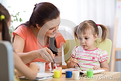 Woman teaches kids painting at kindergarten or playschool Stock Photo