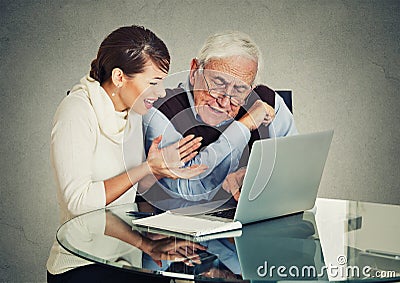 Woman teaching confused elderly man how to use laptop Stock Photo