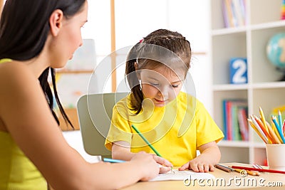 Woman teaching kid to write. Elementary pupil painting with teacher Stock Photo