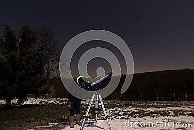 Woman with telescope under winter night sky Woman looking through telescope under starry night. Stock Photo
