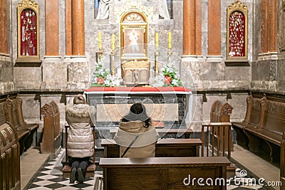 A woman in a temple prays to God. Woman praying in front of altar. Praying woman in front of altar. selected focus Editorial Stock Photo