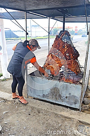 A woman tends to roasting meat at a restaurant on the side of a Editorial Stock Photo