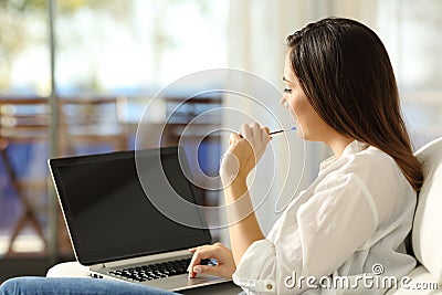 Woman thinking using a laptop with blank screen Stock Photo