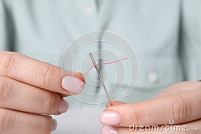 Woman threading needle, closeup view. Sewing equipment Stock Photo