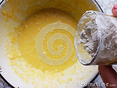 Woman throw flour from glass to bowl with dough Stock Photo