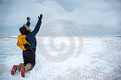 Woman throwing snow while kneeling on frozen wave Stock Photo