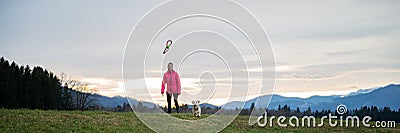 Woman throwing a toy for his pet dog outside in beautiful meadow Stock Photo