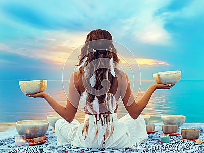 Woman with Tibetan Singing Bowls. Relaxation and Meditation at Sunset Beach. Sound Healing Therapy. Peaceful Women Silhouette Stock Photo