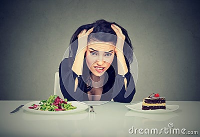 Woman tired of diet restrictions deciding to eat healthy food or cake she is craving Stock Photo