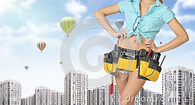 Woman in tool belt standing akimbo. Cropped image Stock Photo
