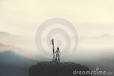 Woman on top of a mountain carries a big surreal key, solution concept Stock Photo