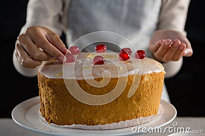 Woman toping a fresh baked cake with cherry Stock Photo