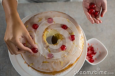 Woman toping a fresh baked cake with cherry Stock Photo