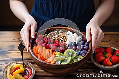 woman topping her acai bowl with fresh fruit Stock Photo