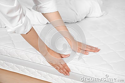 Woman touching soft white mattress on bed, closeup Stock Photo