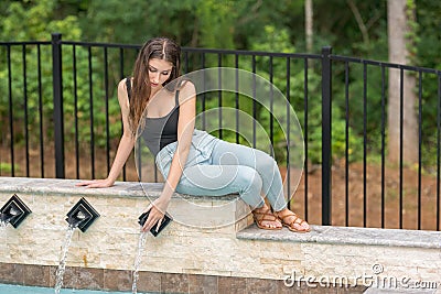 Woman touching water coming out of pool fountain Stock Photo