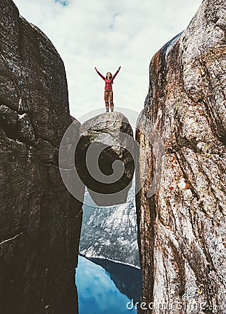 Woman tourist on Kjeragbolten raised hands Travel in Norway Stock Photo