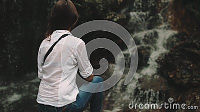 Woman tourist look at splashing tropical waterfall Stock Photo