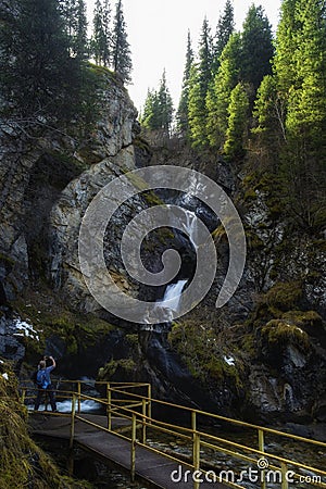 A woman tourist photographs the Kairak waterfall in the mountains of Kazakhstan in Turgen River Gorge, Almaty Editorial Stock Photo