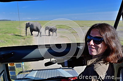 Woman tourist on safari in Africa, car travel in Kenya, elephants in savanna Stock Photo