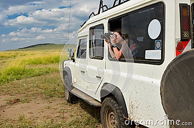 Woman tourist on safari in Africa, travel in Kenya, watching wildlife in savanna with binoculars Stock Photo