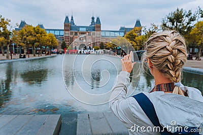 Woman tourist taking photo of the Rijksmuseum in Amsterdam on the mobile phone. Travel in Europe city trip concept Editorial Stock Photo
