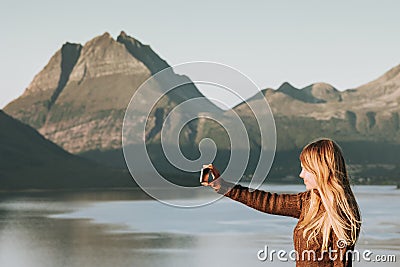 Woman tourist taking selfie by smartphone Travel Lifestyle concept adventure vacations outdoor Norway sunset mountains and sea Stock Photo