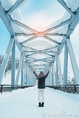 Woman tourist Visiting in Biei, Traveler in Sweater sightseeing Shirahige Waterfall bridge with Snow in winter. landmark and Stock Photo