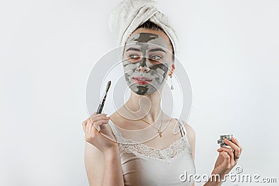 woman in towel with brush applied a black cleansing mask on face isoalted on white Stock Photo