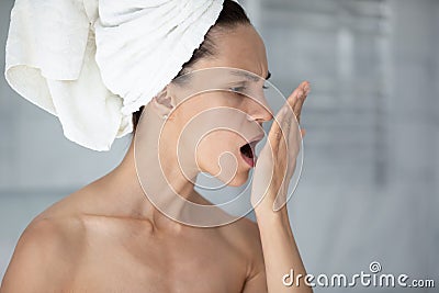 Woman with towel on head opens mouth check breath Stock Photo