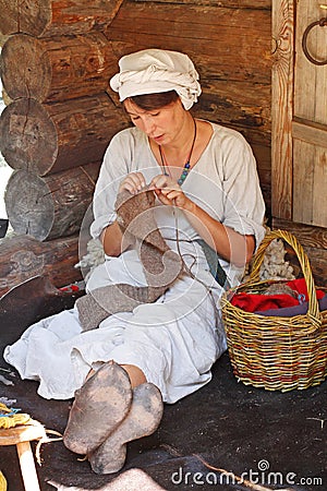 A woman in traditional dress and headscarf engaged in needlework at the festival `Times and epochs` in Moscow Editorial Stock Photo