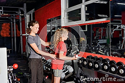 The woman trainer helps the girl when performing exercises with Stock Photo