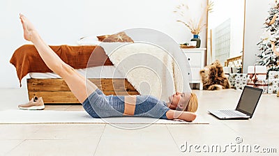 Woman training abdominal muscles lifting legs up lying on floor Stock Photo