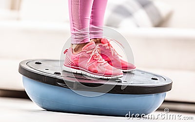 Woman in training shoes stands on a blue balance ball Stock Photo