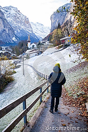 woman traveler in amazing touristic alpine village in winter with famous church and Staubbach waterfall Lauterbrunnen Editorial Stock Photo