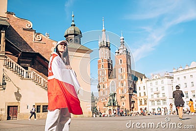 woman traveler covered with poland flag at the center of Krakow town Editorial Stock Photo