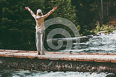 Woman Traveler happy raised hands on bridge over river adventure Travel Stock Photo