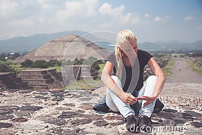 Woman traveler resting on the top after a long hard climb on one of famous ruins of ancient city Maya in Teotihuacan, Mexico wi Stock Photo