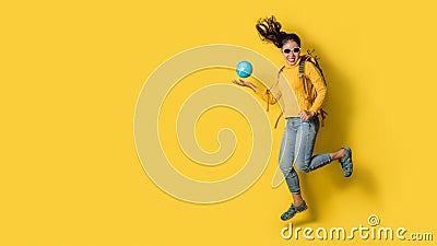 Woman traveler with suitcase, holding ball globe in the hand on Yellow background. Portrait of smiling happy girl with space copy Stock Photo