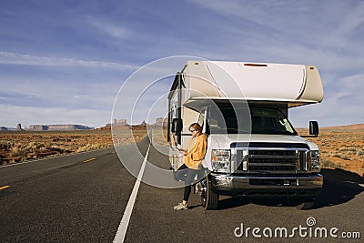 A woman travels by motorhome through Monument Valley in the USA desert and checks her mobile phone parked Stock Photo