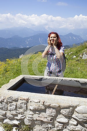 Woman trekker refreshing high in the mountains Stock Photo