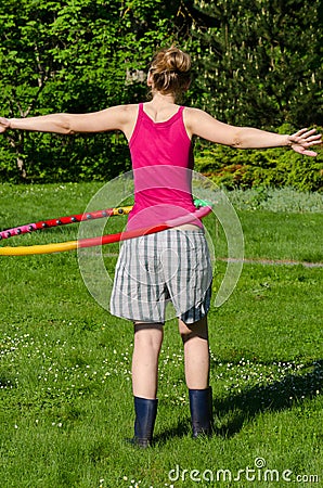 Woman turn spin hula hoop ring on waist in garden Stock Photo