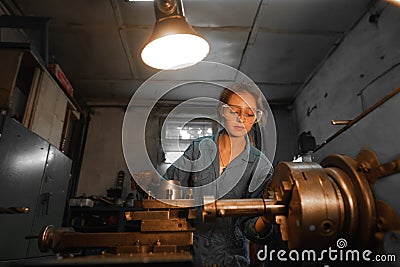Woman turner in production near the lathe. Profession concept Turner, Metalworking, Turning, Industry, Metal. Stock Photo