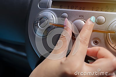 Woman turning button of radio in car. Car Radio Listening. Stock Photo