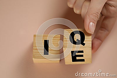Woman turning cube with letters E and I near Q on beige background, above view Stock Photo