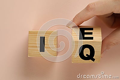 Woman turning cube with letters E and I near Q on beige background, top view Stock Photo