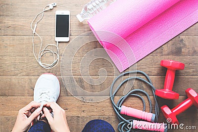 Woman tying up sport shoes, Directly above with sport equipments on wooden floor Stock Photo