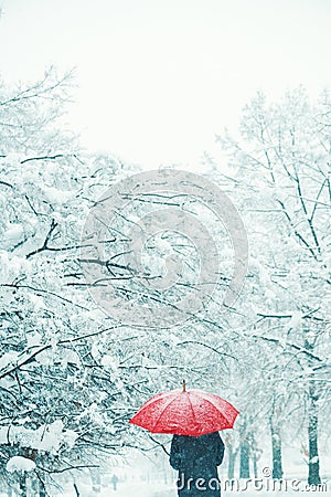 Woman under red umbrella walking in winter snow Stock Photo